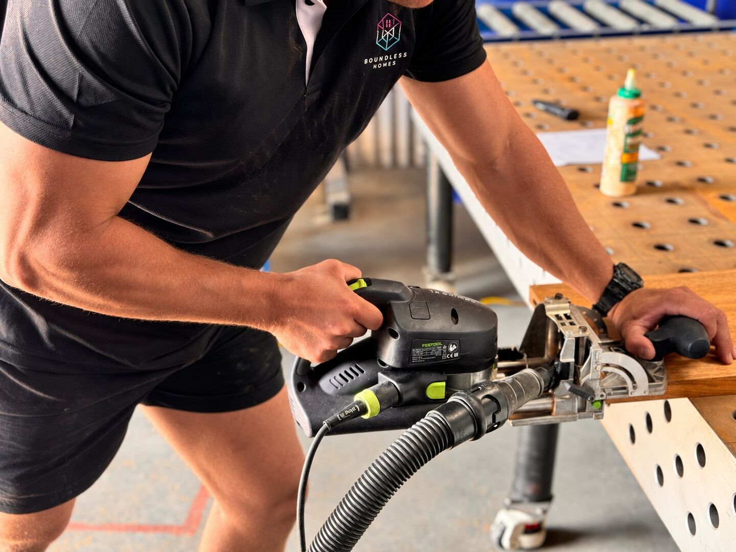 A carpenter cutting a timber joint with a domino jointer at a workbench