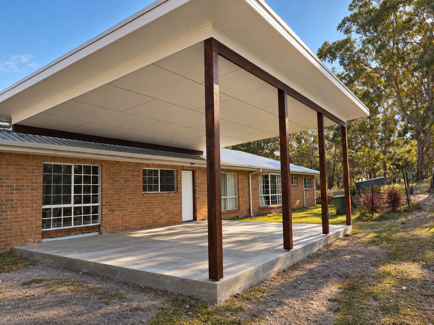 A flyover patio with hardwood posts and insulated roof panels on a brick home